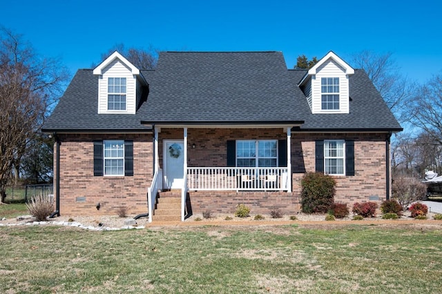 new england style home featuring covered porch, brick siding, crawl space, and a front yard