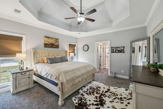 carpeted bedroom featuring a tray ceiling, visible vents, ornamental molding, a ceiling fan, and baseboards