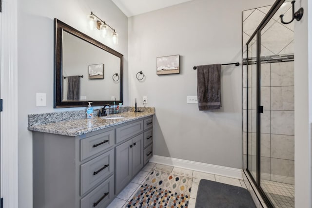 bathroom with tile patterned flooring, a shower stall, vanity, and baseboards