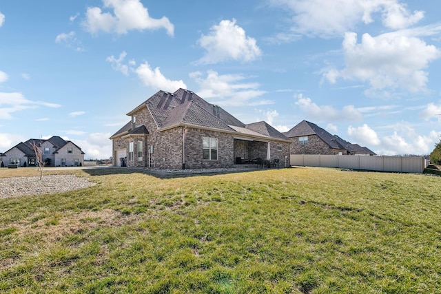 exterior space featuring an attached garage, fence, a lawn, and brick siding