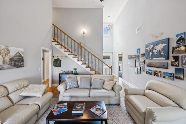 living area with a high ceiling, wood finished floors, visible vents, baseboards, and stairs