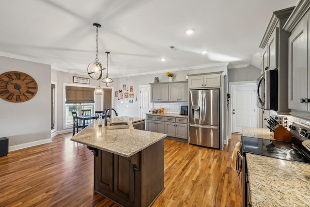 kitchen featuring appliances with stainless steel finishes, wood finished floors, a sink, gray cabinets, and backsplash