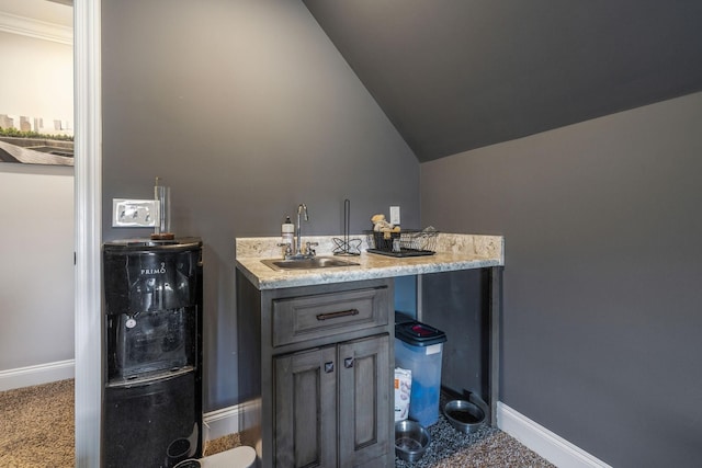 bathroom featuring vaulted ceiling, a sink, and baseboards