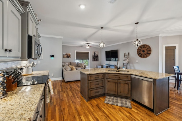 kitchen featuring open floor plan, stainless steel appliances, dark wood-type flooring, and a sink