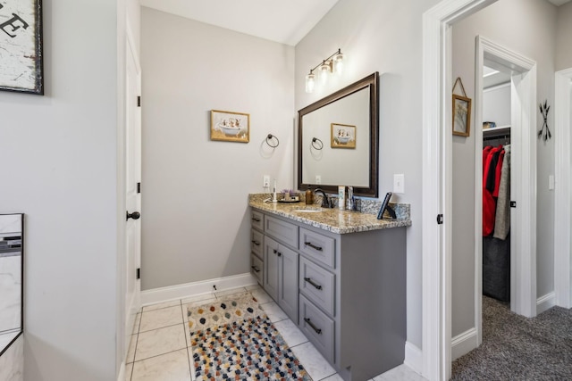 full bath featuring a spacious closet, tile patterned flooring, vanity, and baseboards