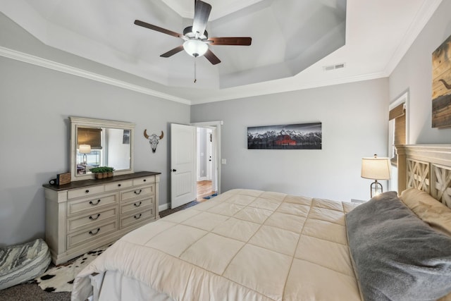 bedroom featuring ornamental molding, a tray ceiling, visible vents, and a ceiling fan