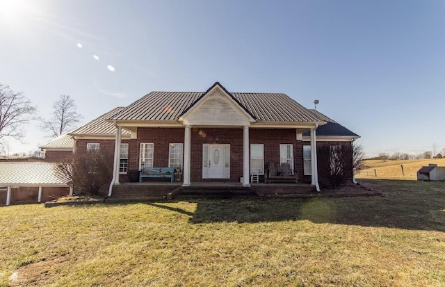 view of front of home with a front yard, a standing seam roof, brick siding, and metal roof