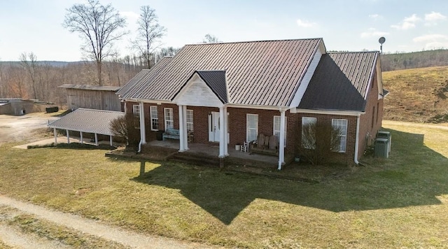 view of front facade featuring metal roof, central AC unit, brick siding, a standing seam roof, and a front yard