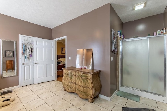 bathroom featuring a textured ceiling, tile patterned flooring, visible vents, baseboards, and a shower stall