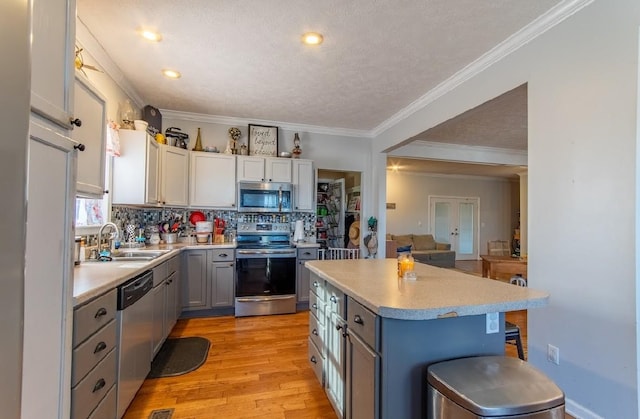 kitchen with a breakfast bar area, light countertops, appliances with stainless steel finishes, a sink, and light wood-type flooring