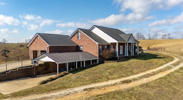 view of front of home featuring a front yard, brick siding, metal roof, and a rural view