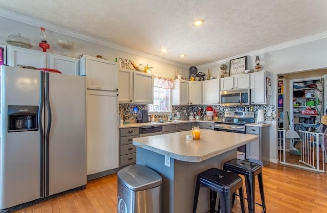 kitchen with light wood-style flooring, a kitchen island, a breakfast bar, stainless steel appliances, and light countertops