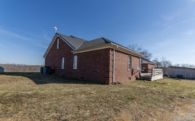 view of home's exterior featuring metal roof, crawl space, brick siding, and a lawn