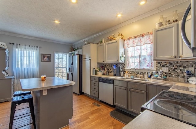 kitchen featuring light wood-type flooring, a kitchen bar, appliances with stainless steel finishes, and gray cabinets