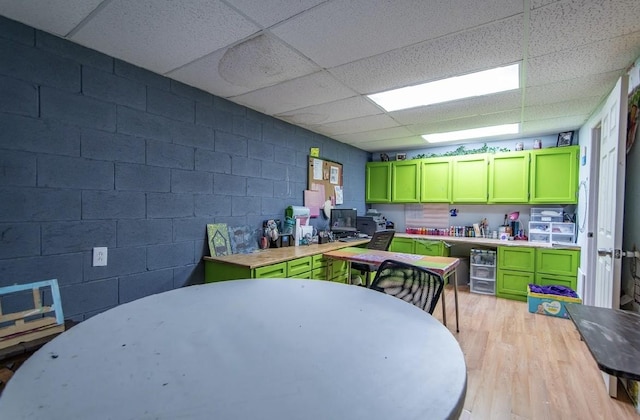 kitchen with green cabinets, wood counters, light wood-style flooring, and concrete block wall