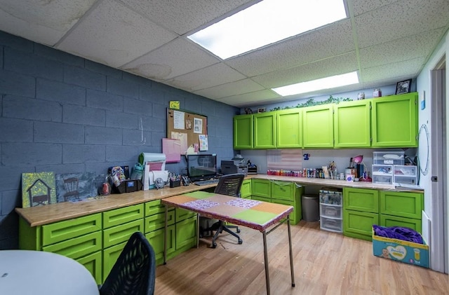 kitchen with light wood-type flooring, wood counters, green cabinetry, and concrete block wall