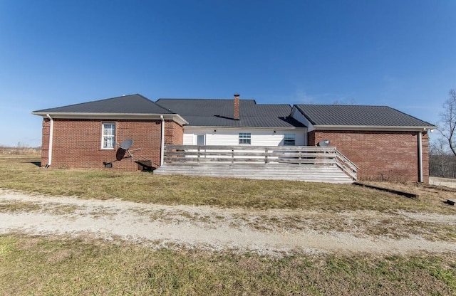 rear view of house featuring brick siding, a lawn, and a chimney