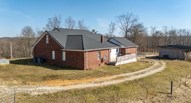 view of side of property with brick siding, dirt driveway, a lawn, crawl space, and metal roof