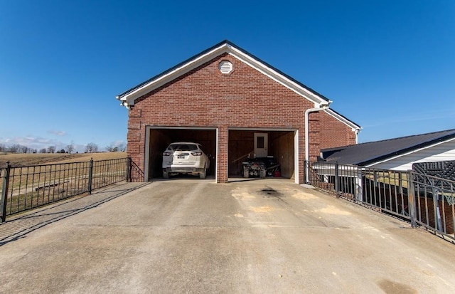 view of home's exterior featuring a garage, driveway, brick siding, and fence