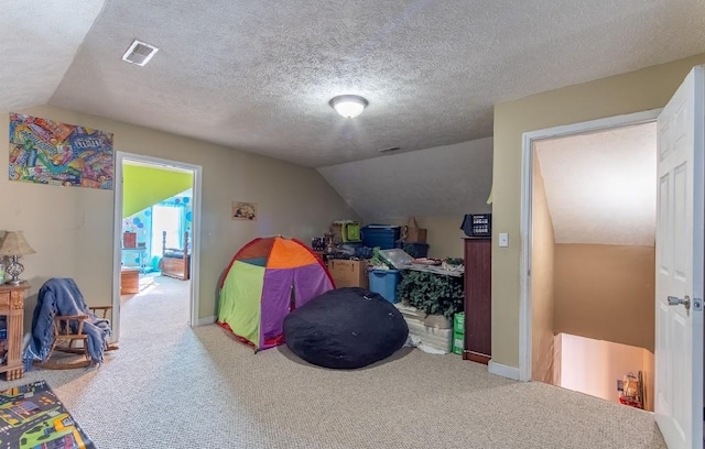 playroom featuring carpet floors, lofted ceiling, visible vents, and a textured ceiling