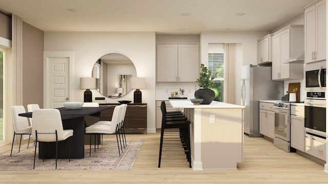 kitchen with a kitchen island, a kitchen breakfast bar, stainless steel appliances, light countertops, and white cabinetry