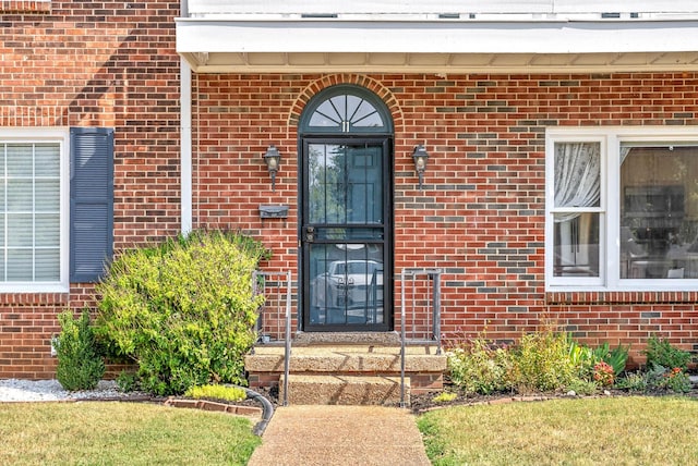 property entrance featuring brick siding and a yard