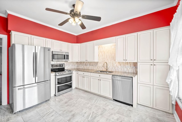 kitchen with light stone counters, stainless steel appliances, crown molding, white cabinetry, and a sink