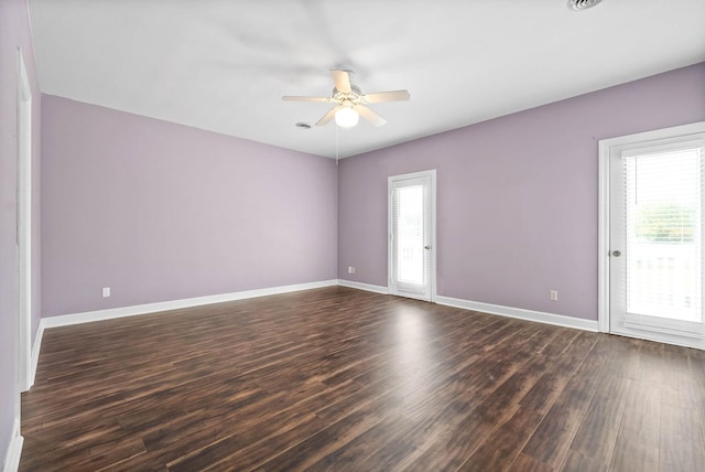 empty room with plenty of natural light, baseboards, and dark wood finished floors