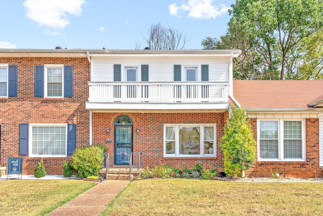 view of front of property with brick siding, a balcony, and a front lawn