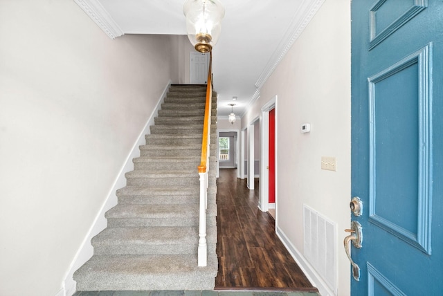 staircase with baseboards, visible vents, crown molding, and wood finished floors