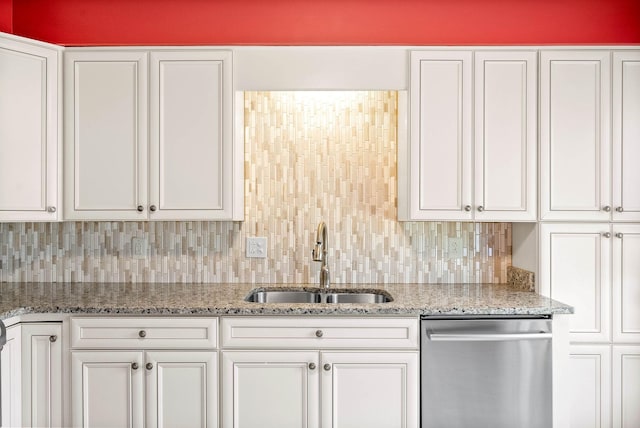 kitchen with a sink, light stone countertops, white cabinetry, and stainless steel dishwasher