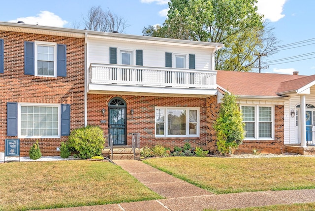 view of front facade with brick siding, a balcony, and a front lawn