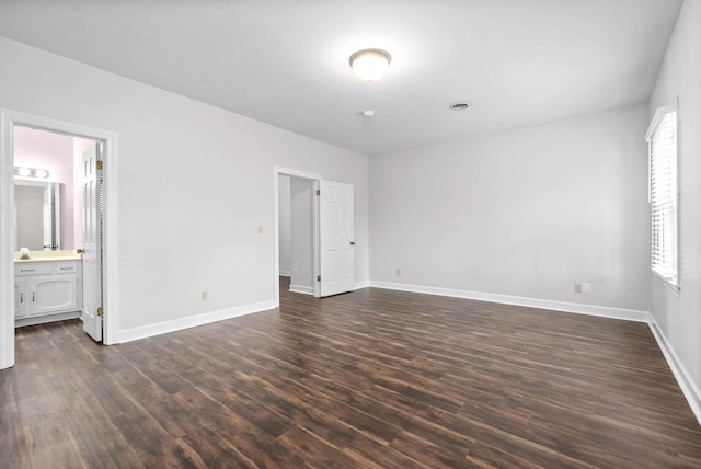 unfurnished bedroom with dark wood-style floors, multiple windows, and baseboards