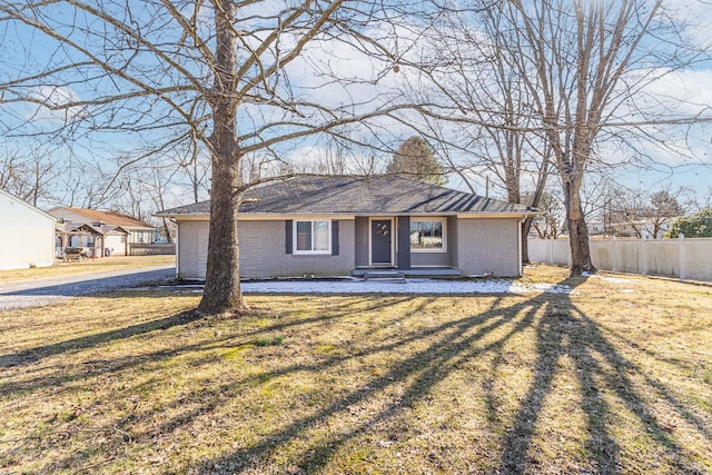 view of front of house featuring a front yard, a chimney, fence, and brick siding