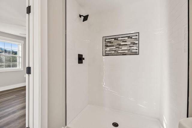 bathroom with a stall shower, wood finished floors, and baseboards