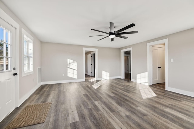 unfurnished living room with visible vents, baseboards, ceiling fan, and dark wood-type flooring