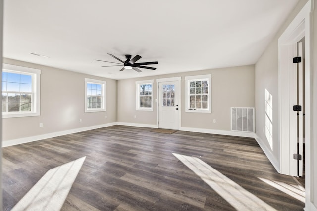 unfurnished living room with dark wood-style floors, baseboards, visible vents, and ceiling fan