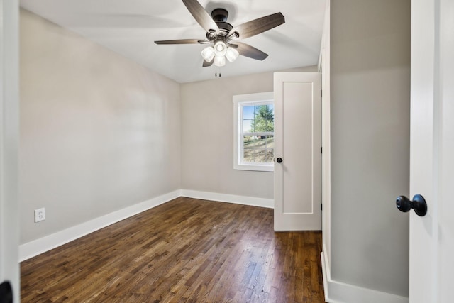 empty room with dark wood-type flooring, a ceiling fan, and baseboards