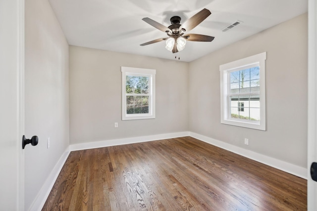 unfurnished room with a wealth of natural light, visible vents, baseboards, and wood finished floors