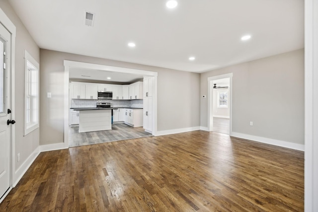 unfurnished living room with baseboards, visible vents, dark wood-type flooring, and recessed lighting