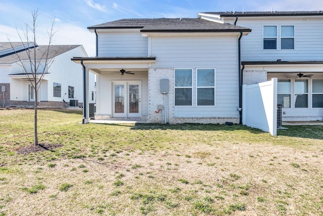 rear view of property with a lawn and a ceiling fan