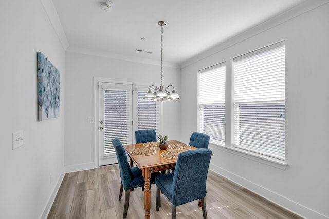 dining space featuring light wood-style flooring, ornamental molding, a chandelier, and baseboards