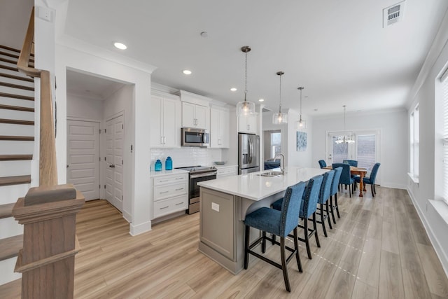 kitchen featuring white cabinetry, stainless steel appliances, a large island with sink, and light countertops