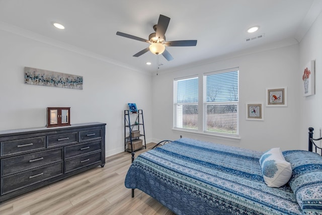 bedroom featuring baseboards, light wood finished floors, visible vents, and crown molding