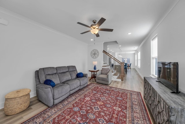 living area with baseboards, ornamental molding, stairway, and light wood-style floors