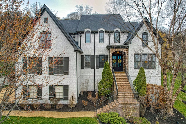 french country style house featuring stairs, french doors, and roof with shingles