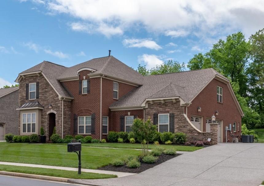 view of front of house featuring concrete driveway, stone siding, cooling unit, a front yard, and brick siding