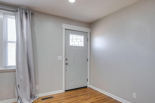 foyer featuring light wood-type flooring, baseboards, and visible vents