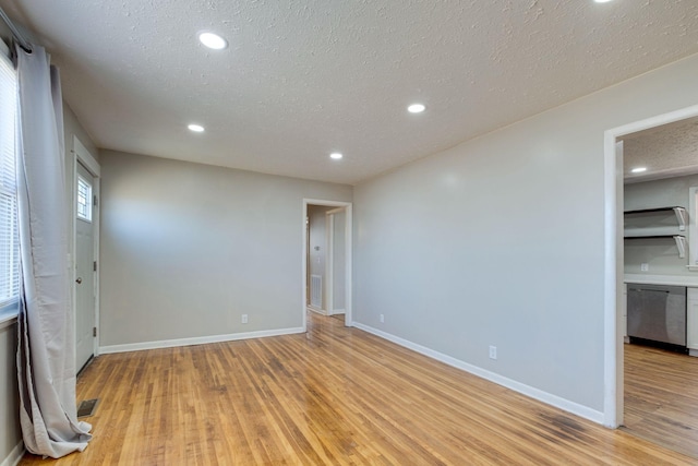 spare room featuring a textured ceiling, recessed lighting, visible vents, baseboards, and light wood finished floors