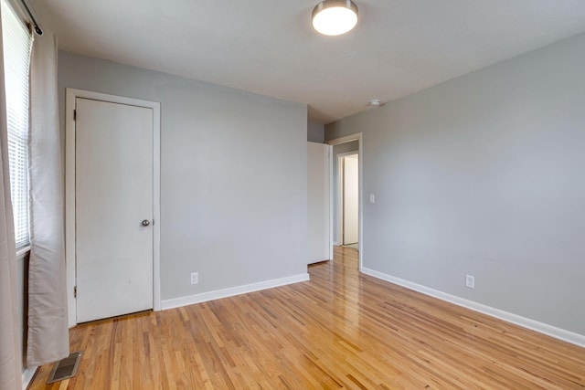 unfurnished bedroom with visible vents, light wood-style flooring, and baseboards